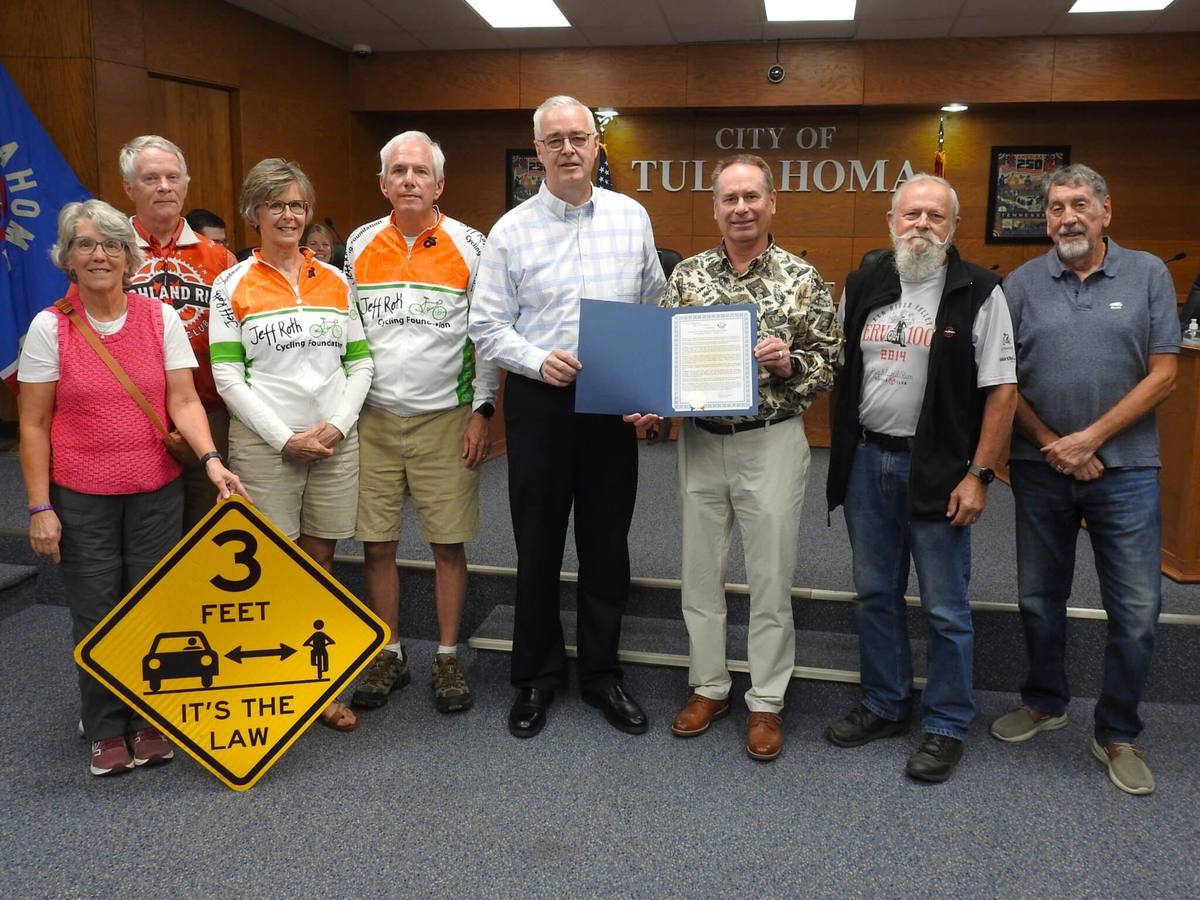 Club members and supporters, some in Highland Rim and Jeff Roth Cycling Foundation jerseys, stand with the Mayor at Tullahoma City Hall holding the proclamation and a yellow 3 FEET, IT'S THE LAW sign.